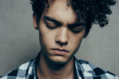 Ekose gömlekli adam kıvırcık saçlı ciddi yüz ifadesi var.