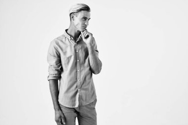 Havalı saç stili olan yakışıklı bir adam ellerini arka planda tutarak poz veriyor.