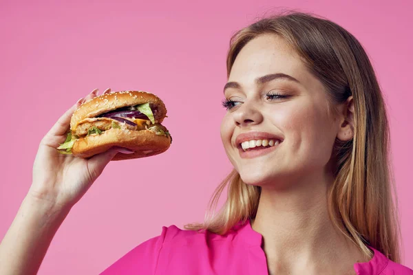 Schattig vrolijk vrouw in roze shirt hamburger voedsel dieet — Stockfoto