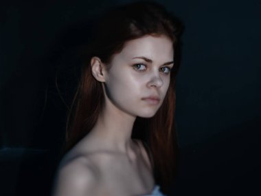 Çıplak omuzlu, açık tenli, esmer bir kadın.