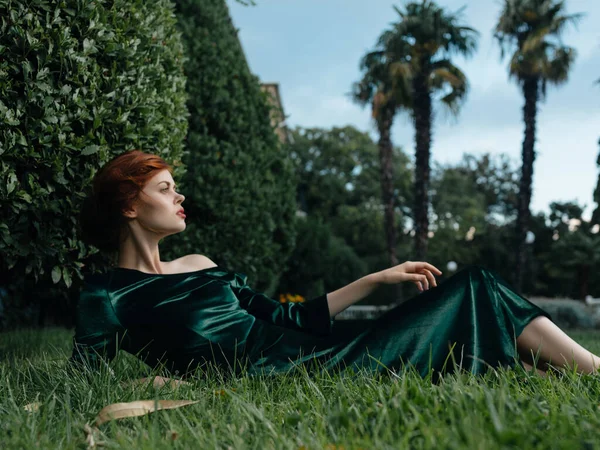 Ελκυστική γυναίκα σε πράσινο φόρεμα βρίσκεται στη διακόσμηση γρασίδι — Φωτογραφία Αρχείου