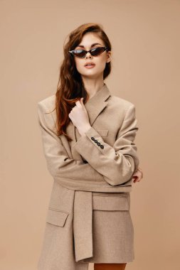 Bej arka planda paltolu kızıl saçlı kadın yakın plan görüntüsü vardı.