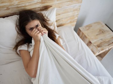 Kadın yatakta, yorganın altında yatıyor. Sabah yaşam tarzı.