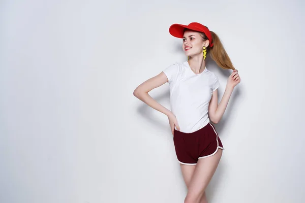 Vidám fiatal lány piros sapkában pózol divat nyár kék háttér — Stock Fotó
