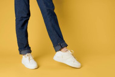 Kadın bacakları kırpılmış beyaz ayakkabılar modern stil sarı arka plan