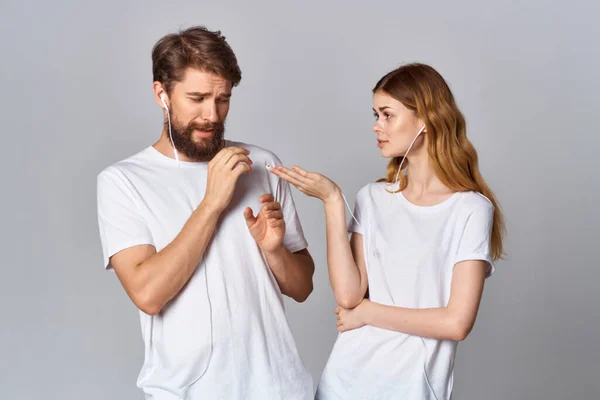 Vrolijk jong paar in witte t-shirts met koptelefoon luisteren naar muziek vreugde vriendschap — Stockfoto