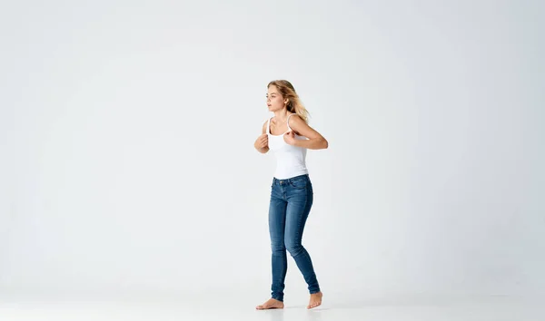 Красива жінка в джинсах танцює босоніж легкий фон — стокове фото