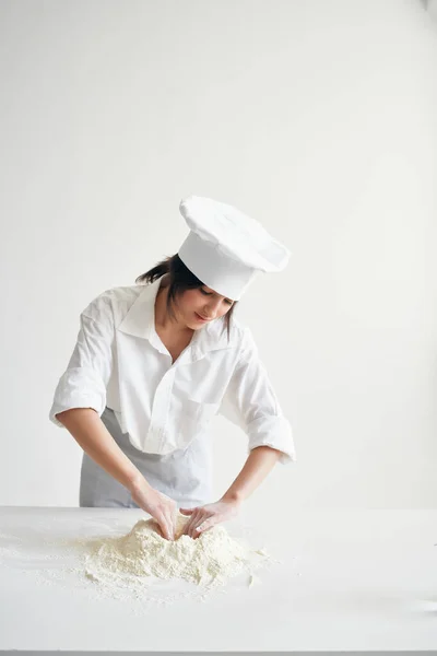 Mulher em chefs uniforme peneira farinha massa de trabalho na cozinha — Fotografia de Stock