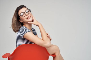 Kırmızı koltukta oturan gözlüklü güzel bir kadın.