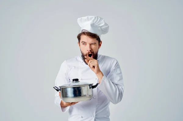 Un uomo in uniforme cuochi una padella nelle sue mani cercando lavoro cibo — Foto Stock