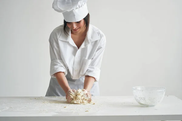 woman baker in cook uniform works with dough flour products