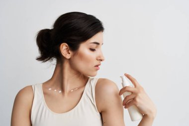 Beyaz tişörtlü kadın ellerinde losyonla cilt temizliği yapıyor.