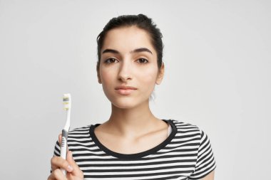 Çizgili tişörtlü kadın diş fırçası ağız hijyeni.