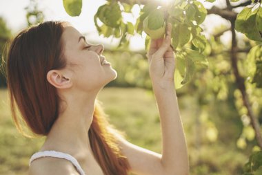 Beyaz elbiseli kadın doğa yeşili ağaçlardan temiz hava bırakır.