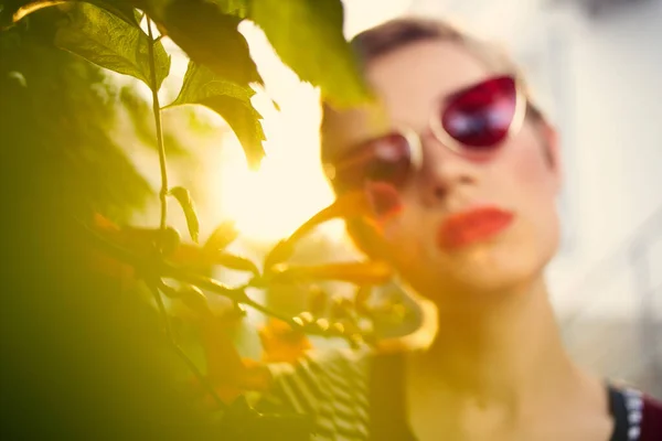 Kvinna med kort hår bär solglasögon utomhus blommor dekoration — Stockfoto