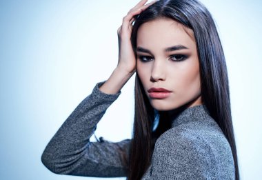 Güzel esmer, parlak makyajlı, yakın çekim pozu veren.