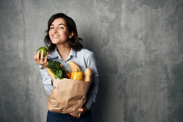 Mujer con un paquete de alimentos vegetales alimentos saludables fondo oscuro —  Fotos de Stock
