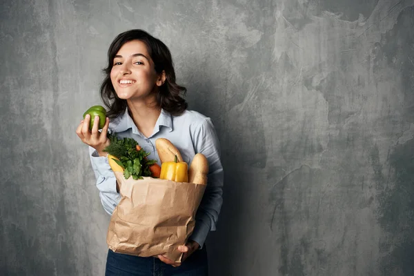 Mujer con un paquete de alimentos vegetales alimentos saludables fondo oscuro —  Fotos de Stock