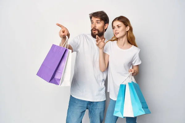 Ellerinde paketler olan kadın ve erkek alışverişte indirim yapıyorlar. — Stok fotoğraf