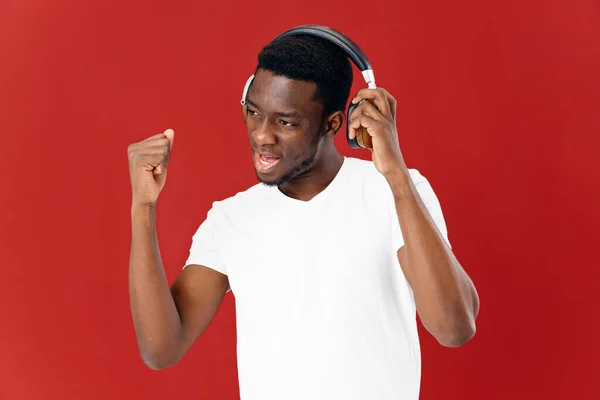 Hombre africano apariencia en auriculares música emociones rojo fondo — Foto de Stock