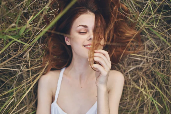 Beyaz elbiseli güzel bir kadın çimenlerin üzerinde dinleniyor. — Stok fotoğraf