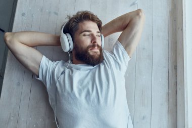 Beyaz tişörtlü adam pencerede uzanıyor kulaklık takıyor yaşam tarzı