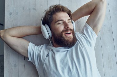 Pencere kenarında uzanmış, kulaklık takmış tatlı bir adam.