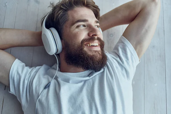 Man in wit t-shirt liggend op de vensterbank met hoofdtelefoon Lifestyle — Stockfoto