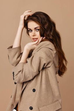 Çekici poz veren güzel kadın ceketi. Bej arka plan.