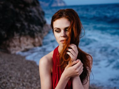 Uçurumun kenarındaki kırmızı elbiseli kadın moda yapıyor.