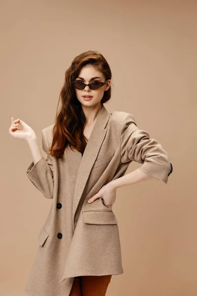 Romantic woman in a coat on a beige background glasses on the face — Stock Photo, Image