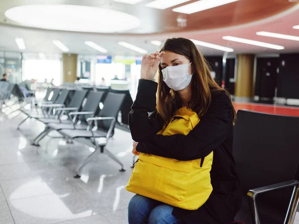 Mujer en el aeropuerto con máscara médica esperando pasajero mochila amarilla — Foto de Stock