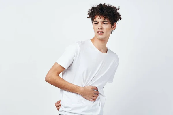 Ricci ragazzo in un bianco t-shirt tenendo il suo stomaco diarrea disagio — Foto Stock