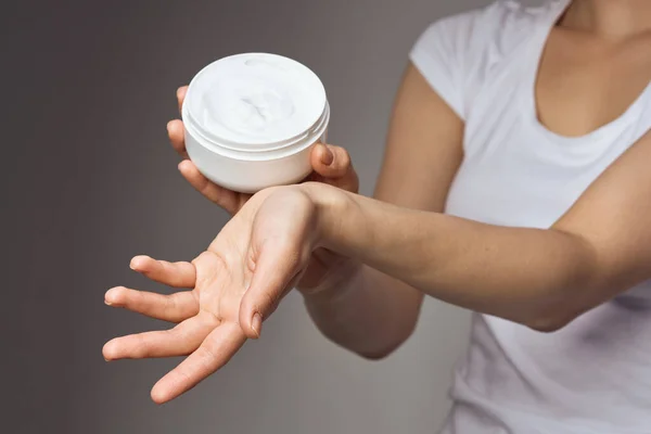 Mulher em t-shirt branca mantém creme nas mãos cuidados com a pele hidratante higiene da saúde — Fotografia de Stock