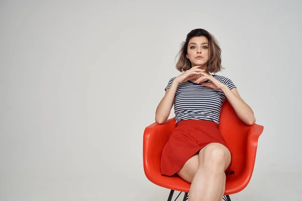 Mulher em uma camiseta listrada sentado na cadeira vermelha corte vista glamour — Fotografia de Stock