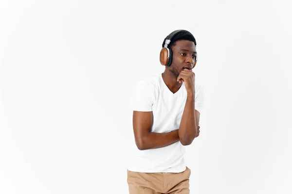 Hombre de aspecto africano en la música auriculares en el fondo de luz de estilo moderno — Foto de Stock