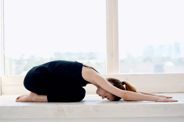Vrouw in de buurt van het raam yoga prestaties meditatie flexibiliteit — Stockfoto