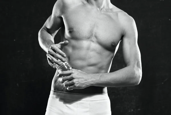 Atleta masculino em shorts brancos corpo inflado fisiculturista o fundo escuro — Fotografia de Stock