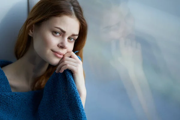 Ładna kobieta siedzi przy oknie z niebieskim uśmiechem w kratkę w domu — Zdjęcie stockowe