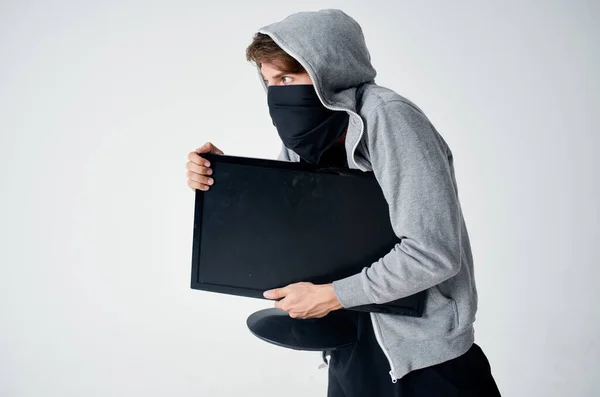 A man in a mask a thief with a monitor in his hands crime — Stock Photo, Image