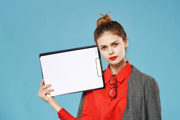 Woman in a red shirt with a jacket holds a sheet of paper Copy Space blue background — Stock Photo, Image