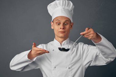 Elinde kepçeyle neşeli bir aşçı, profesyonel bir aşçı.