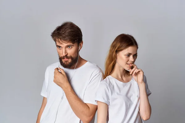 Man och kvinna i vita t-shirts står bredvid vänskapsmusik i hörlurar — Stockfoto