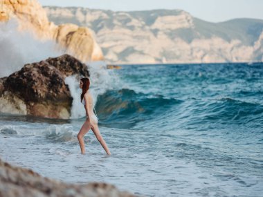 Okyanus dalgalarının yanındaki kadın bikiniyi sallıyor.