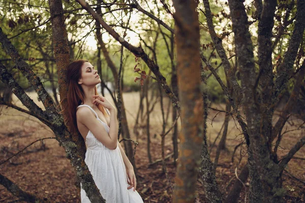 Femme en robe blanche appuyée sur un arbre forêt promenade loisirs — Photo