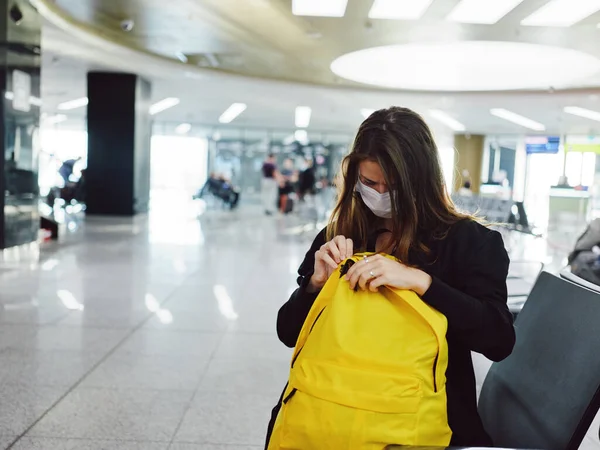 Femme en masque médical frappe aéroport sac à dos jaune attente — Photo