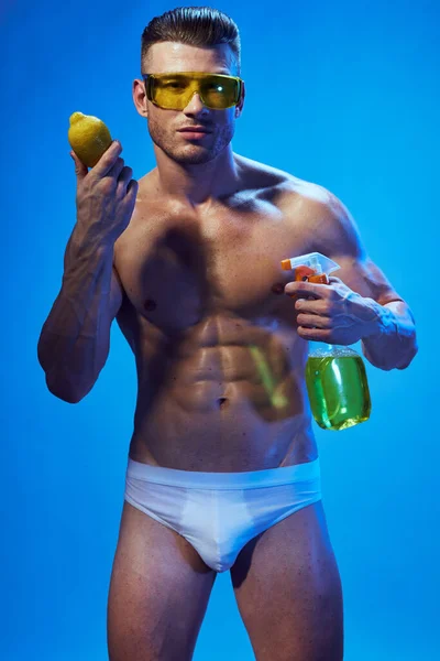 Bir aptalın içinde şişkin bir vücudu olan atletik bir adam limonu eline bastırıyor. — Stok fotoğraf