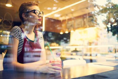 Kısa saçlı bir kadın kafe kokteyl tatilinde bir masada oturuyor.