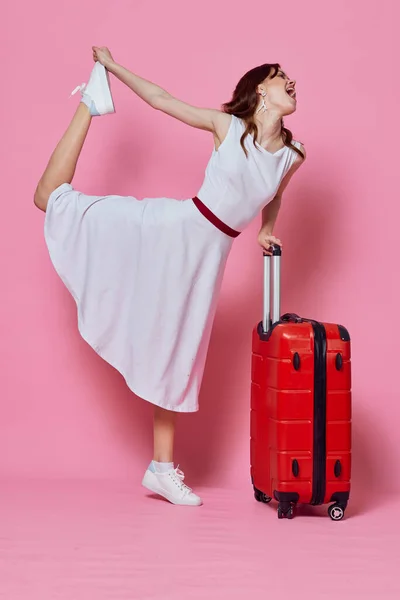 Woman with red suitcase white dress emotions travel pink background — Stock Photo, Image