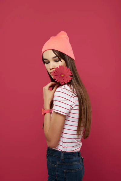 Morena vistiendo un sombrero rosa flor roja maquillaje decoración rosa fondo —  Fotos de Stock